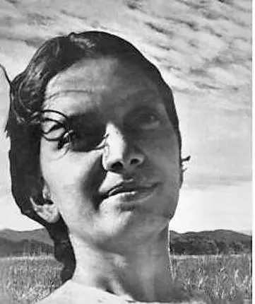 Archival photograph of Kalpana Datta outdoors, her head turned slightly to one side, with clouds and an open field behind her.