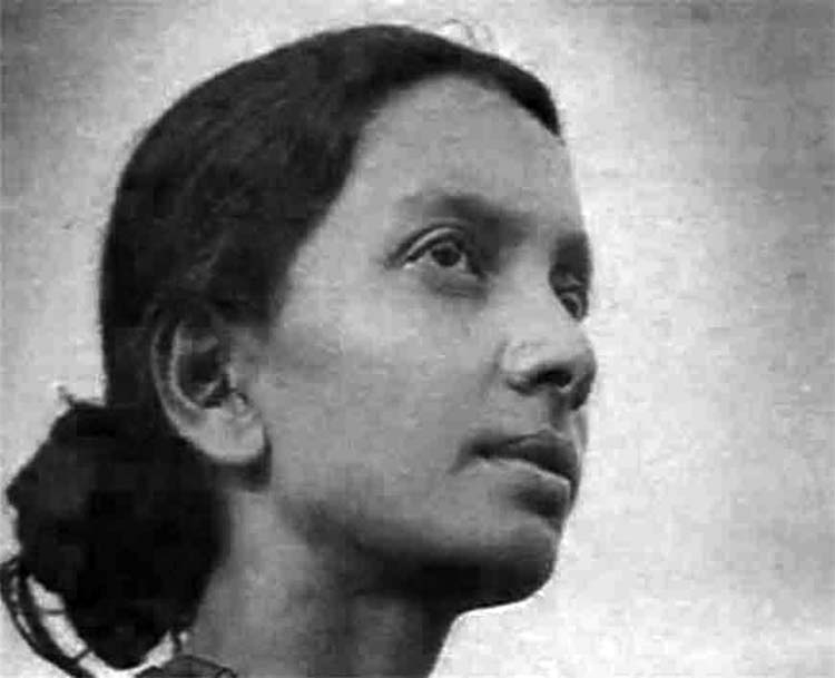 Archival black-and-white close portrait of a young Kalpana Datta in three-quarter profile, looking upward and to her right against a plain pale background.